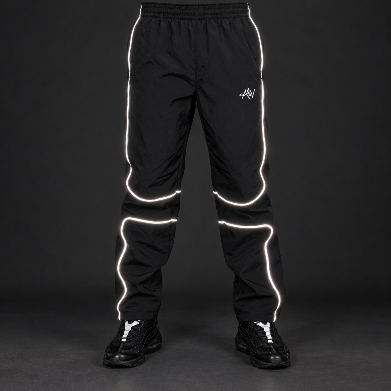 Front view of the black AIVWEAR reflective track pants on a plain studio background